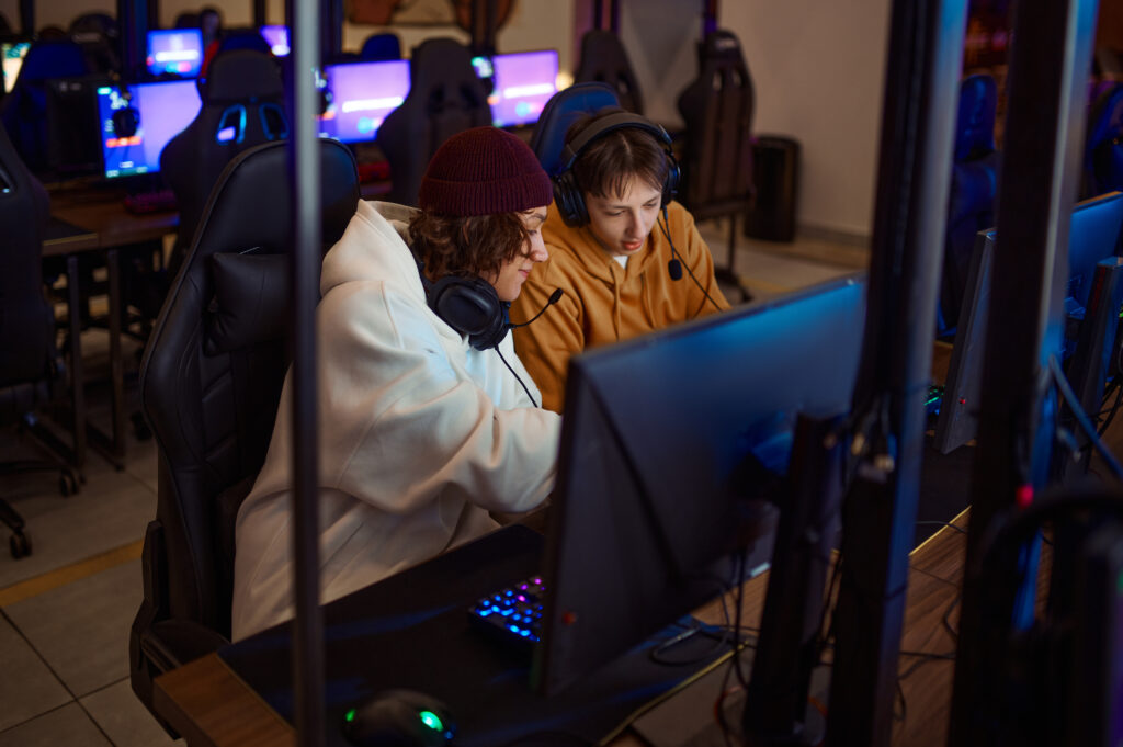 Two gamers having fun in gaming club. Virtual entertainment, e-sport tournament, cybersport lifestyle. Male person leisures in internet cafe